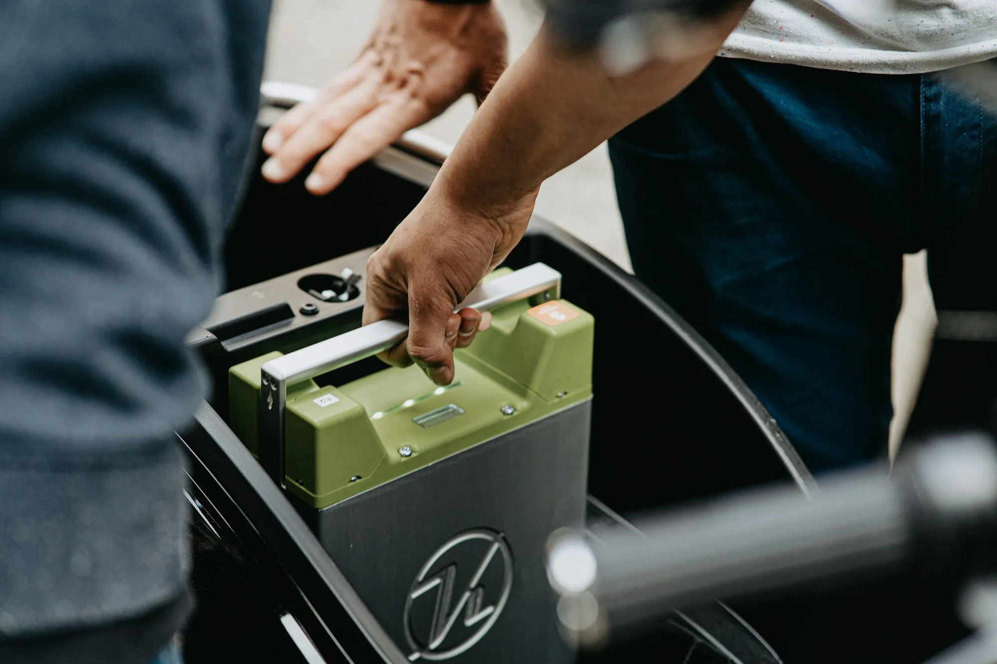 A rider lifting a swappable battery pack into a light electric vehicle