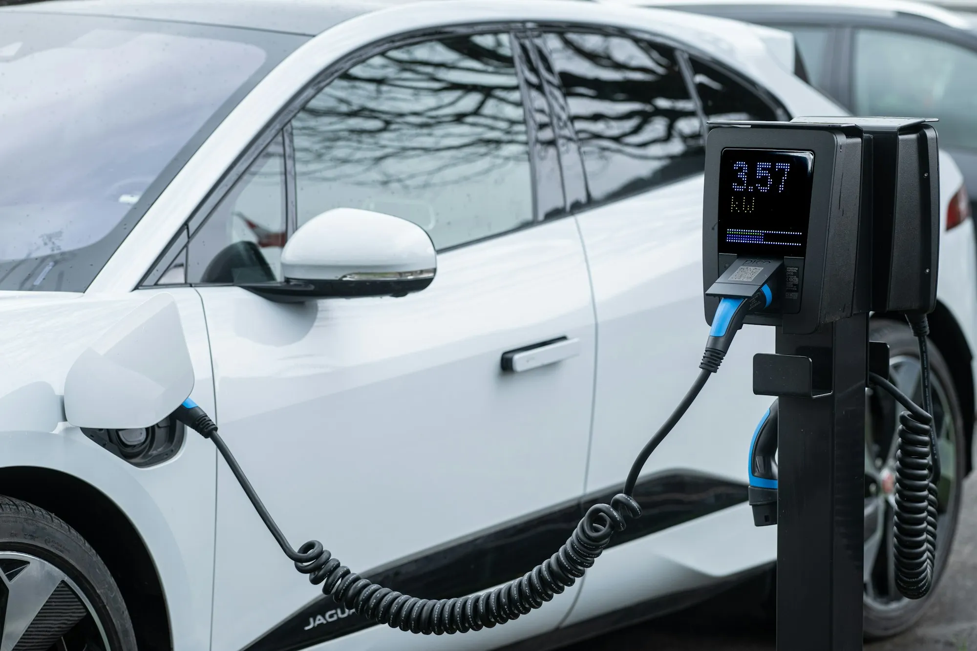 A white electric car charging at a station